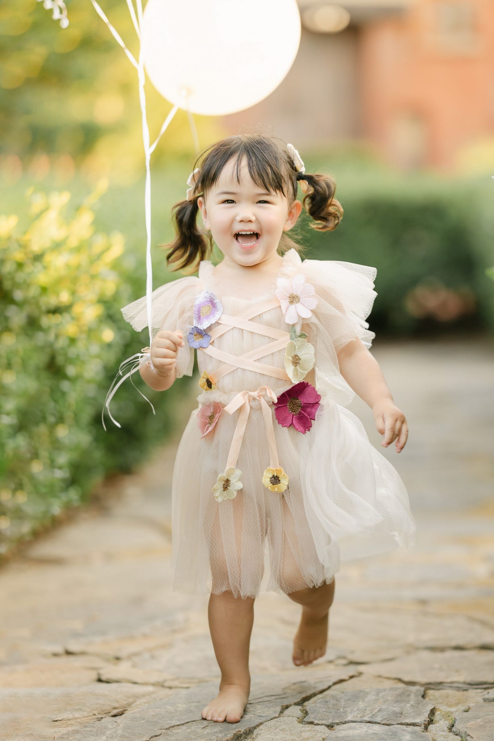 toddler girl running with balloons